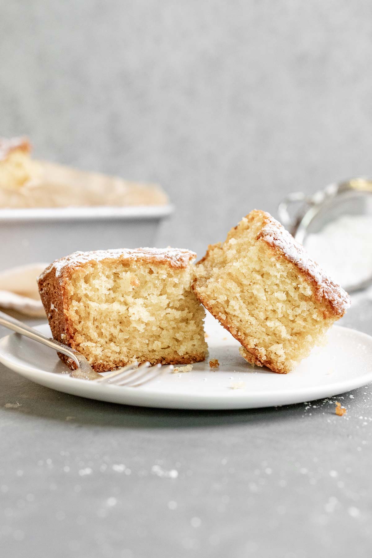 Butter Cake dusted with powdered sugar sliced on plate with fork