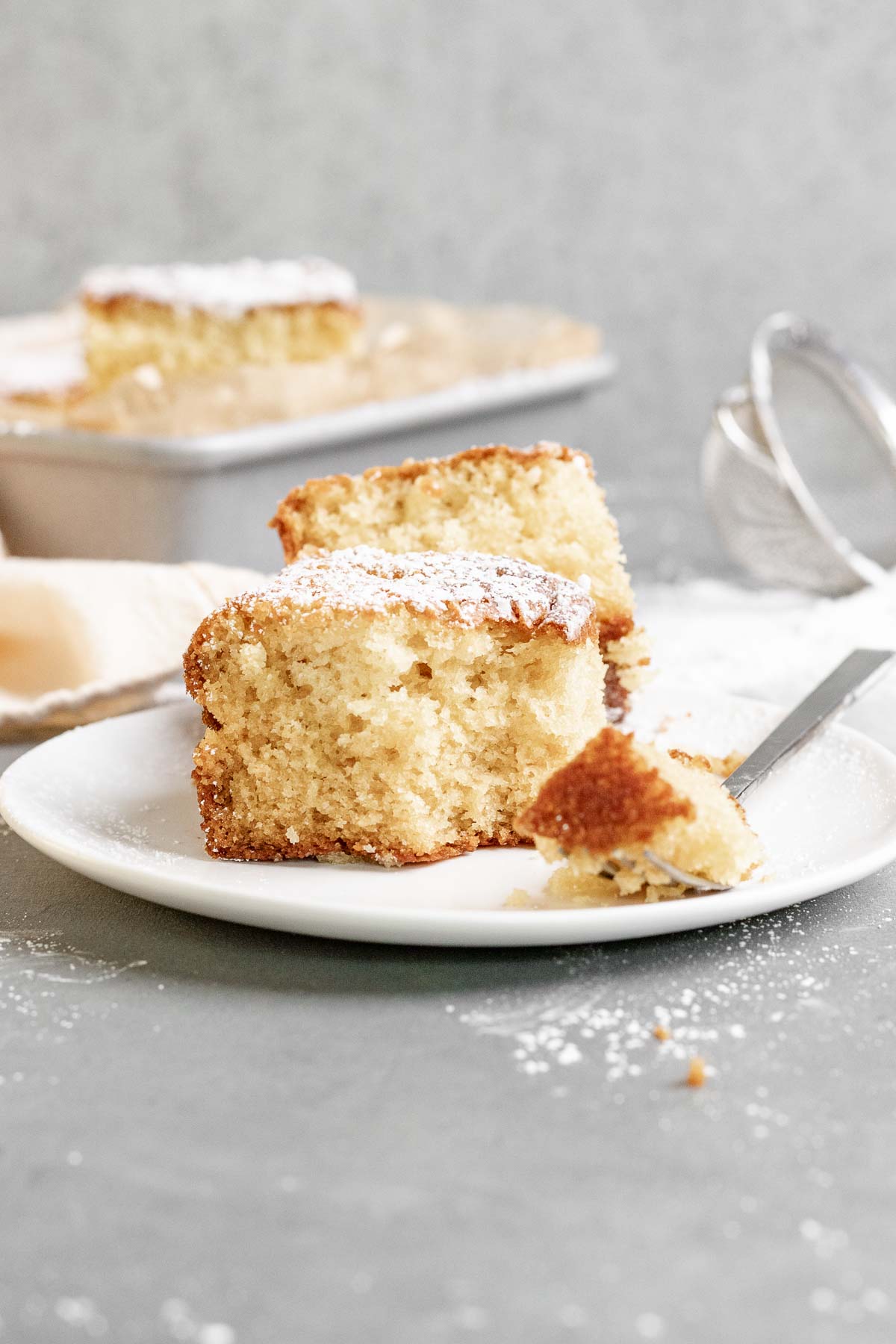 Butter Cake dusted with powdered sugar sliced on plate with fork