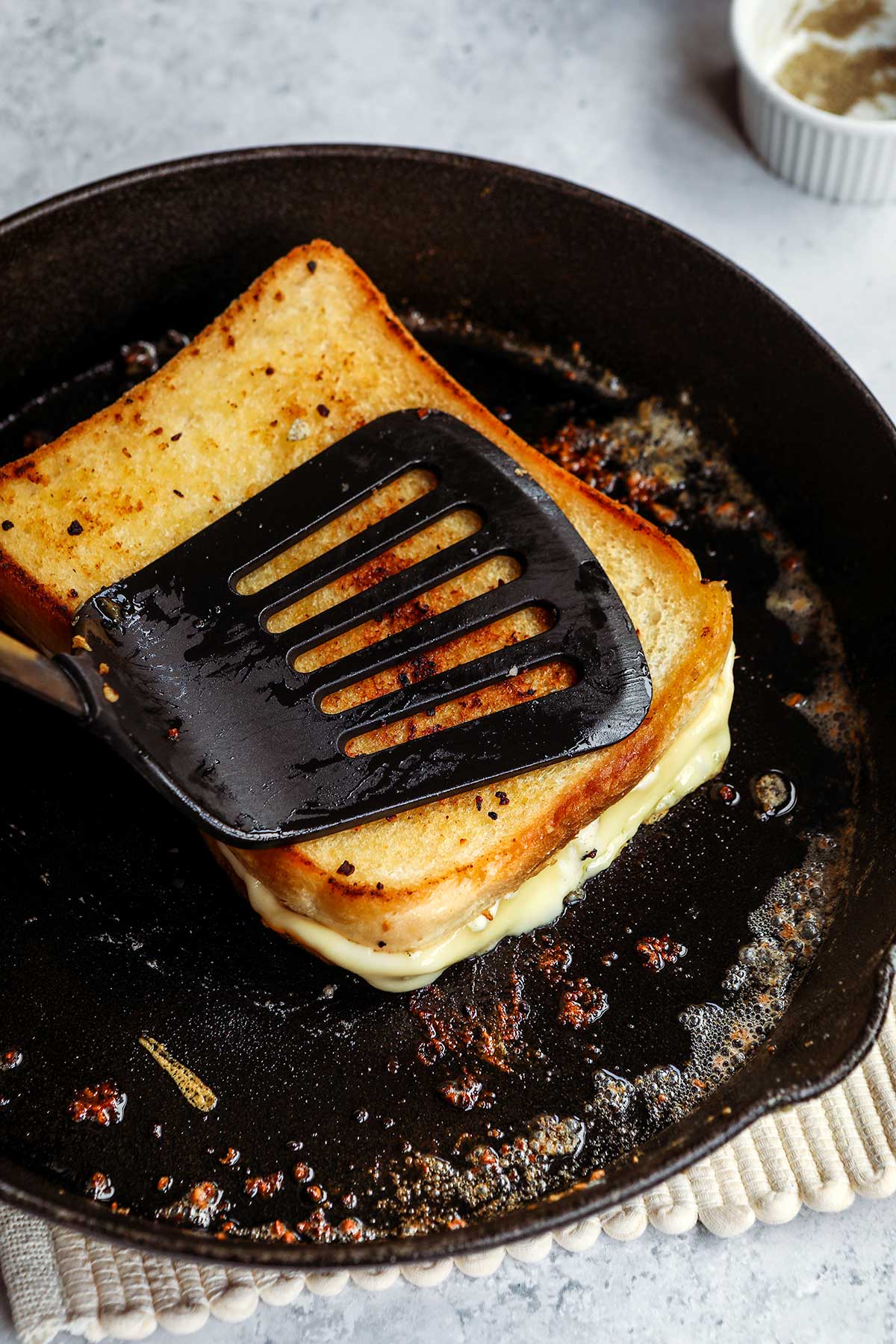 Garlic Butter Four Cheese Grilled Cheese in Pan partially cooked with spatula on top