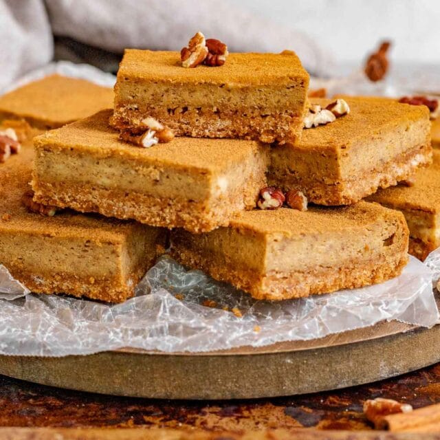 Gingerbread Cheesecake Bars sliced on a board with parchment