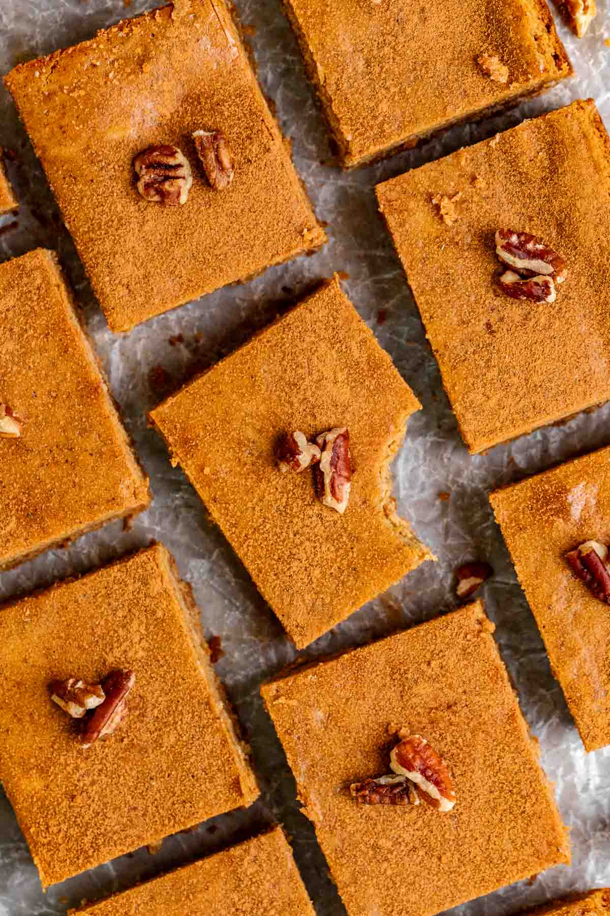 Gingerbread Cheesecake Bars sliced on a board with parchment