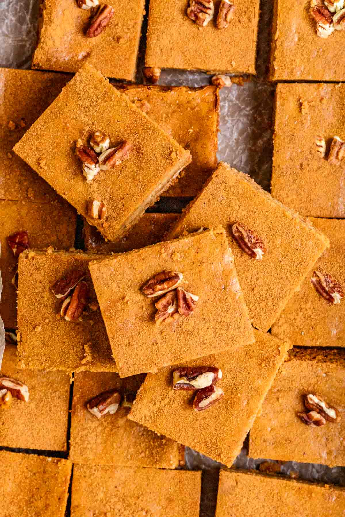 Gingerbread Cheesecake Bars sliced on a board with parchment