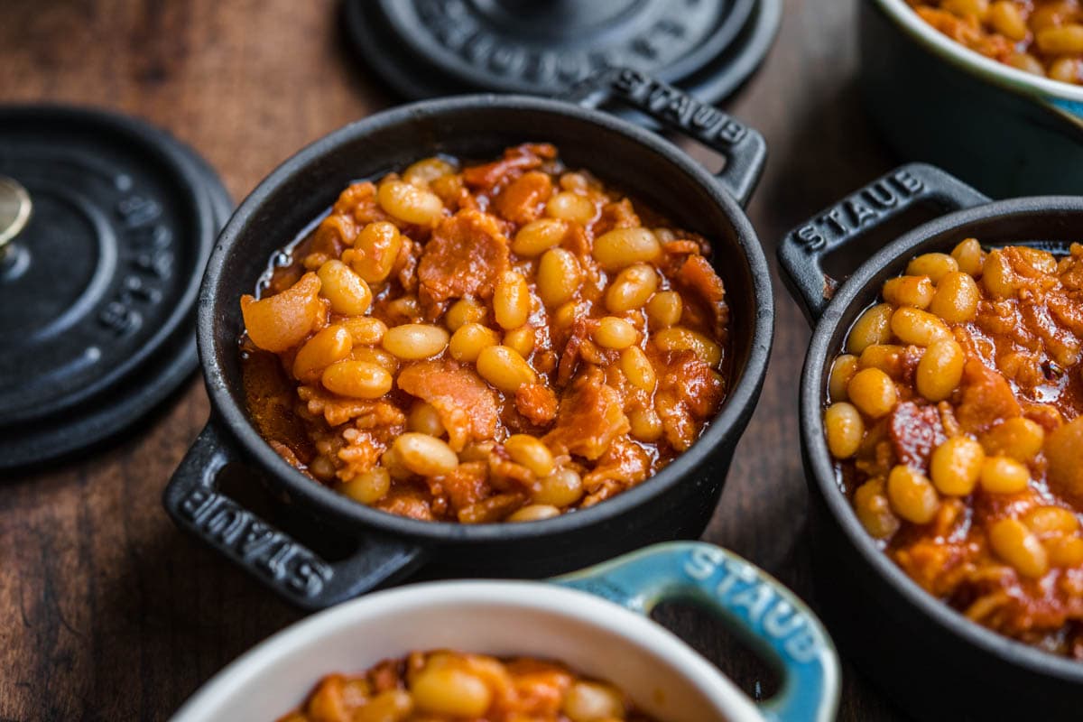 Homemade Pork and Beans with bacon and sauce in small cast iron pots for serving