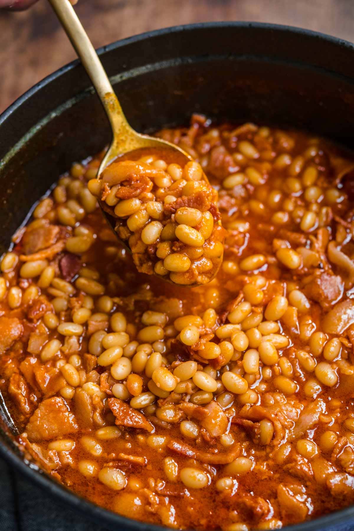 Homemade Pork and Beans with bacon and sauce in pot with spoon