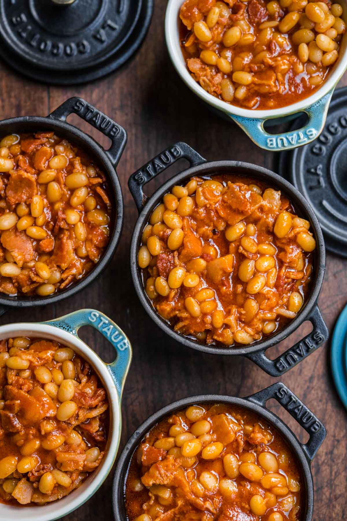 Homemade Pork and Beans with bacon and sauce in small cast iron pots for serving