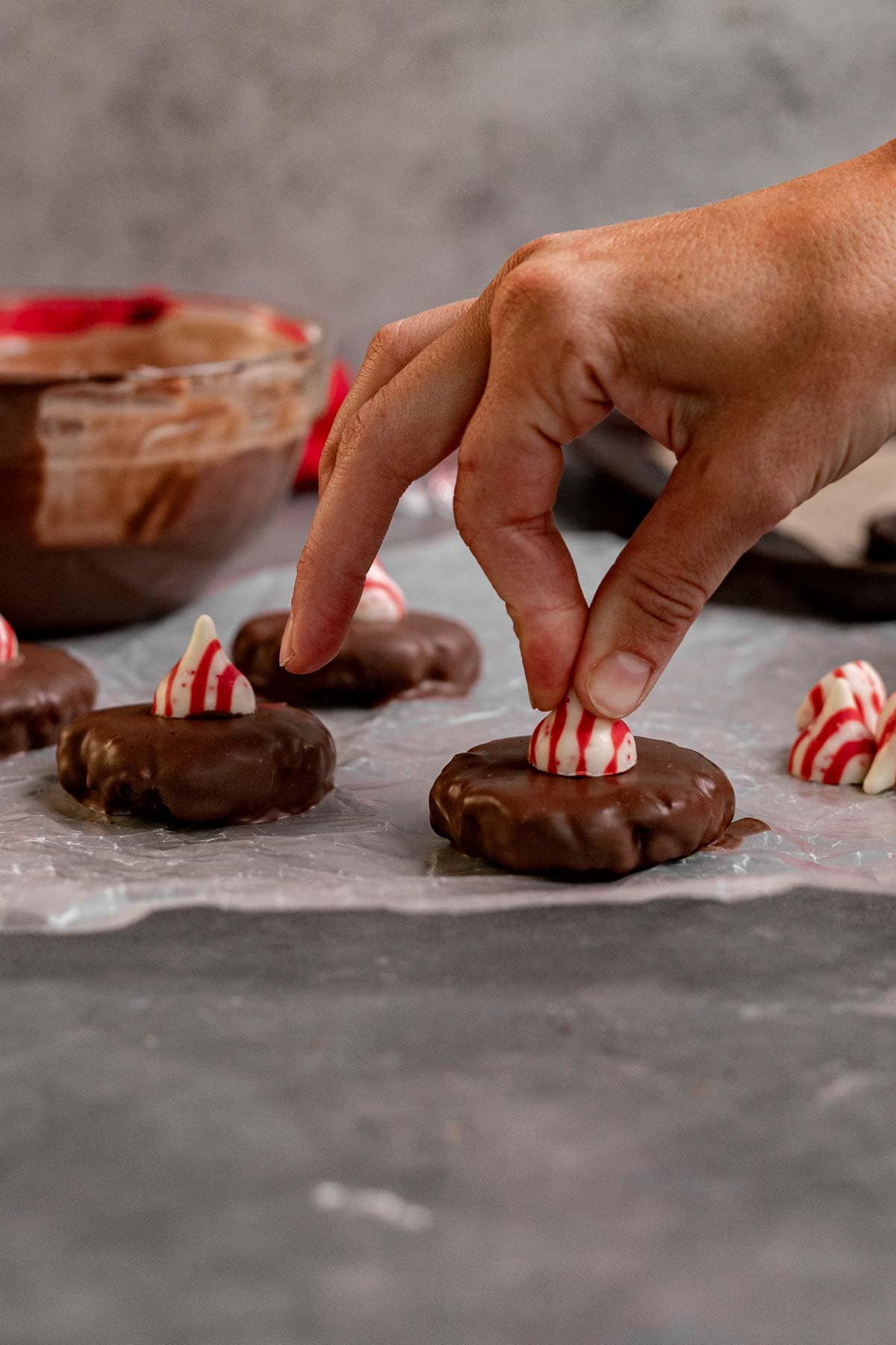 No Bake Peppermint Oreo Blossoms placing striped kiss on top of coated cookie