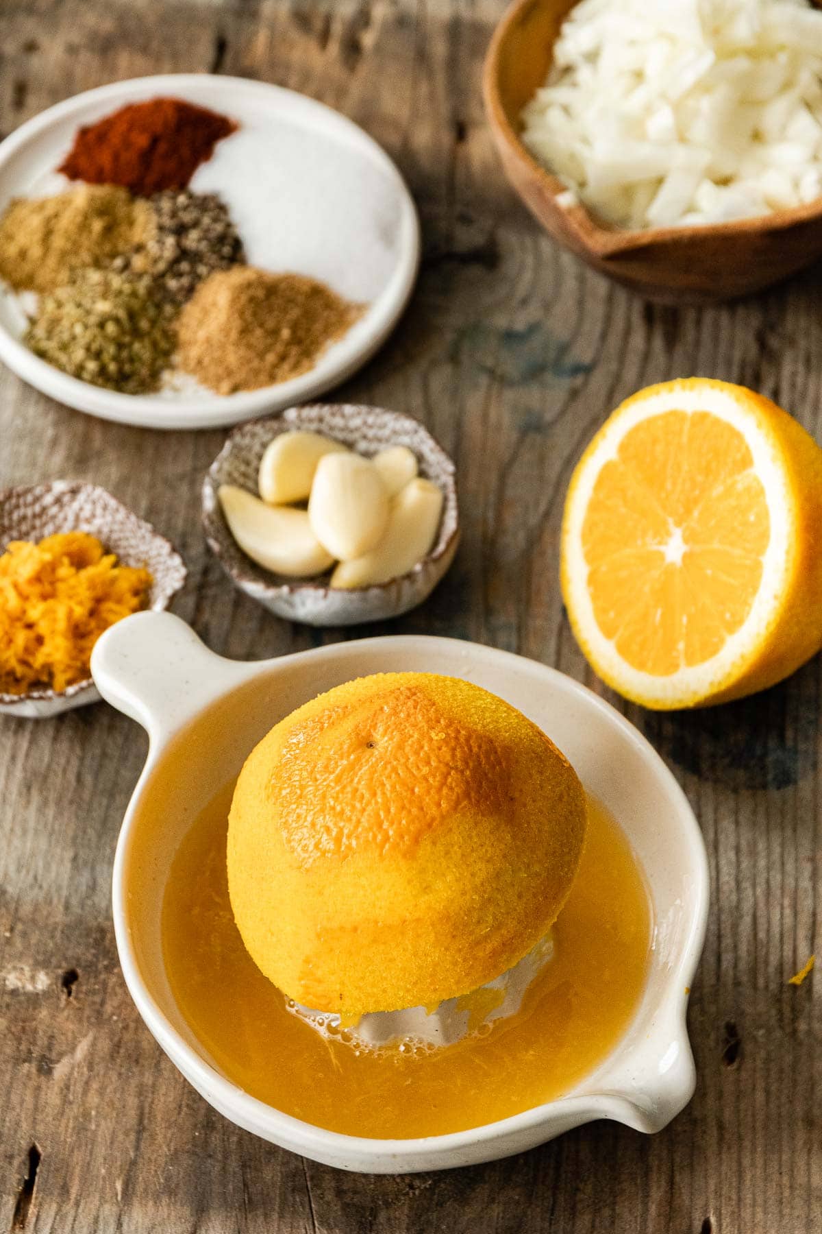 Orange being juiced with spices on plate for Pork Carnitas (Oven)