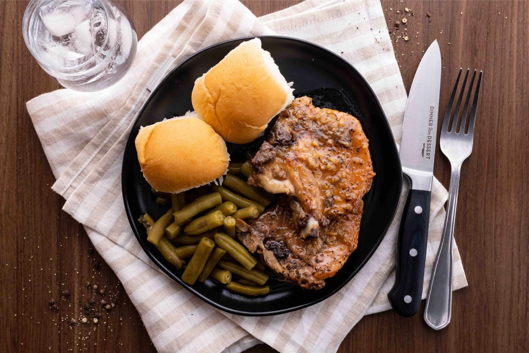 Slow Cooker Brown Sugar Garlic Pork Chops on plate with green beans and dinner rolls