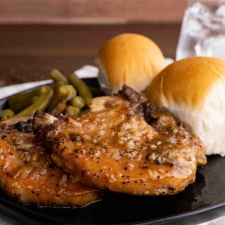 Slow Cooker Brown Sugar Garlic Pork Chops on plate with green beans and dinner rolls
