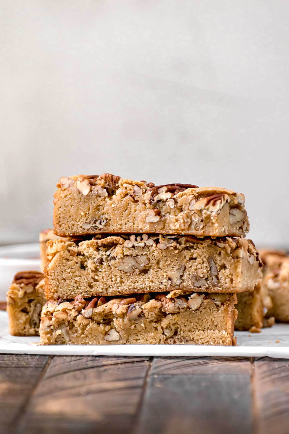 Maple Pecan Bars stacked on top of white parchment paper.