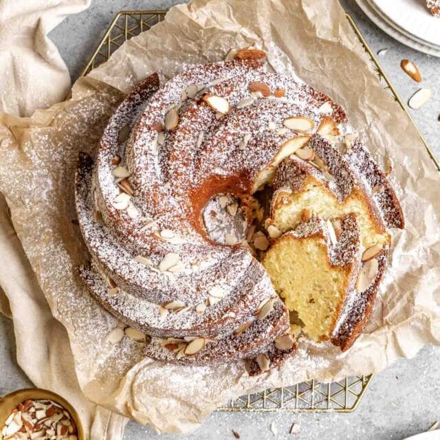 Almond Bundt Cake dusted with powdered sugar and sliced on parchment