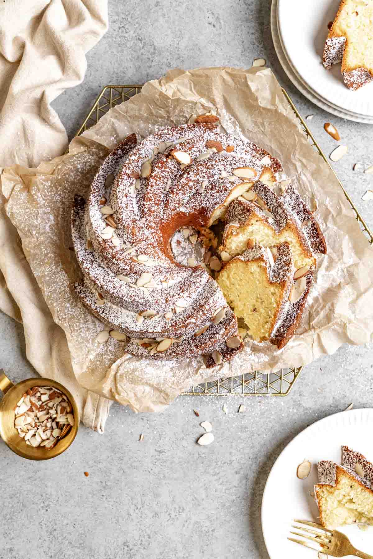 Almond Bundt Cake dusted with powdered sugar and sliced on parchment