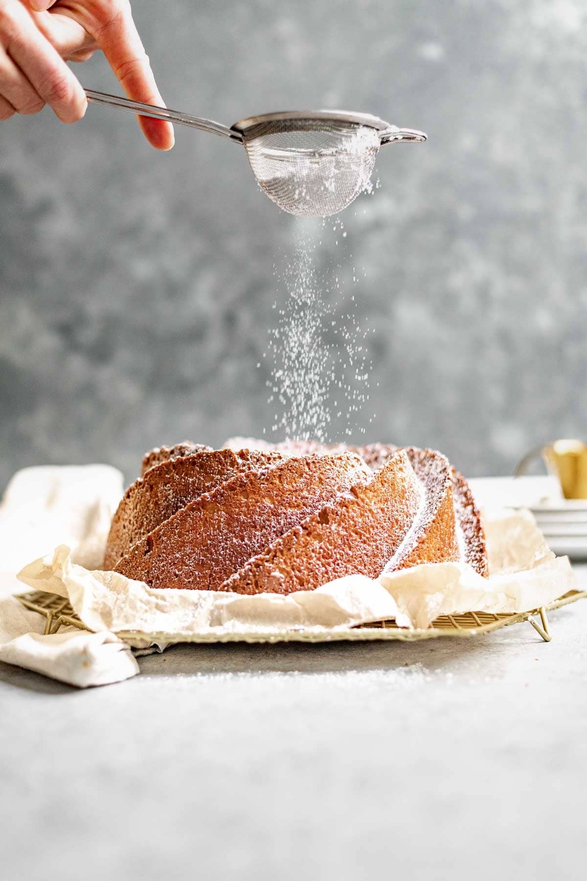 Almond Bundt Cake dusted with powdered sugar on parchment