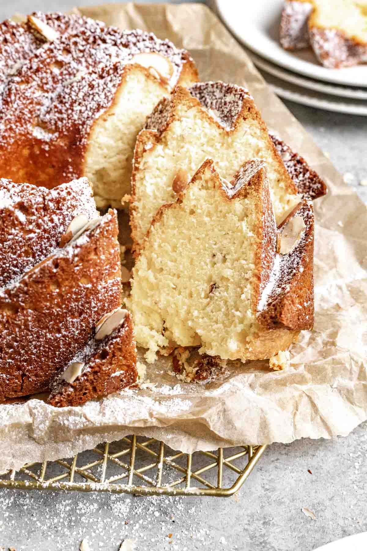 Almond Bundt Cake dusted with powdered sugar and sliced on parchment