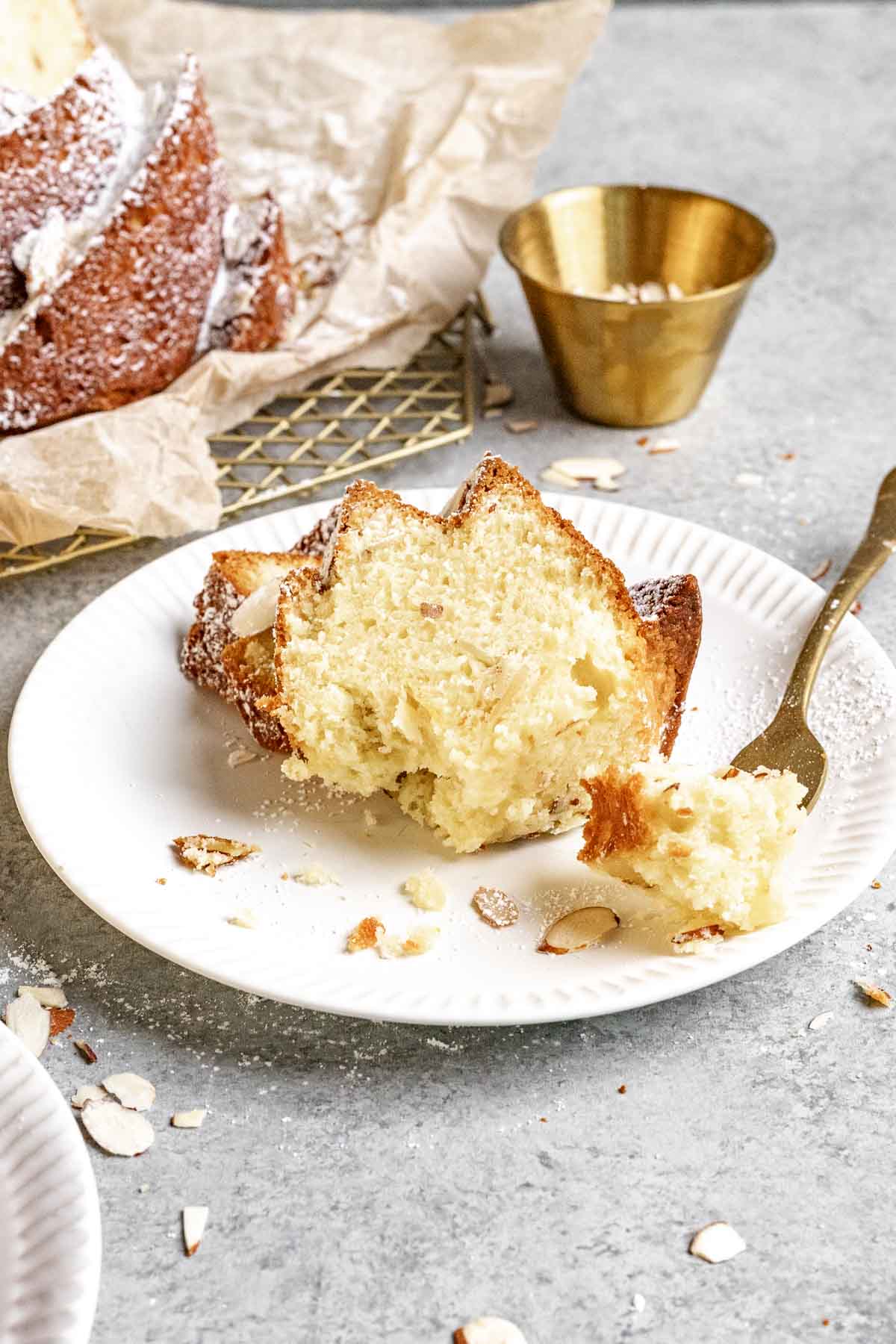 Almond Bundt Cake dusted with powdered sugar sliced on plate