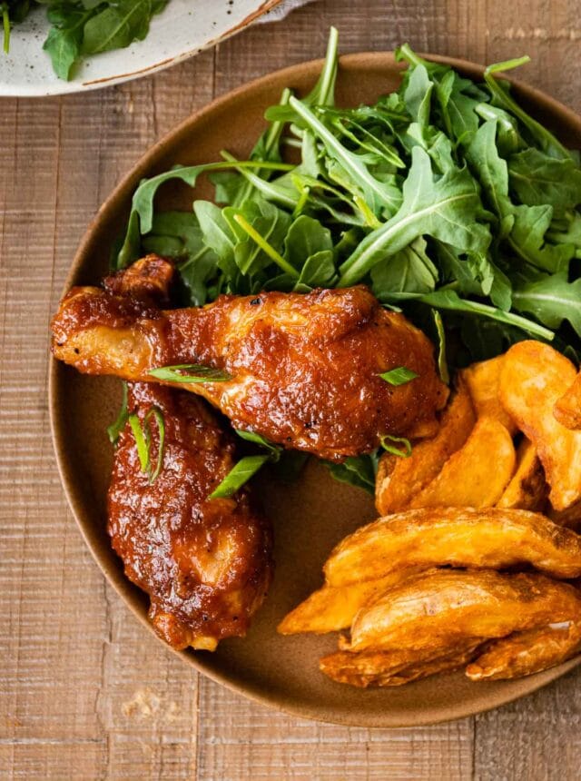 Applesauce BBQ Chicken on dinner plate with arugula salad and potato wedges