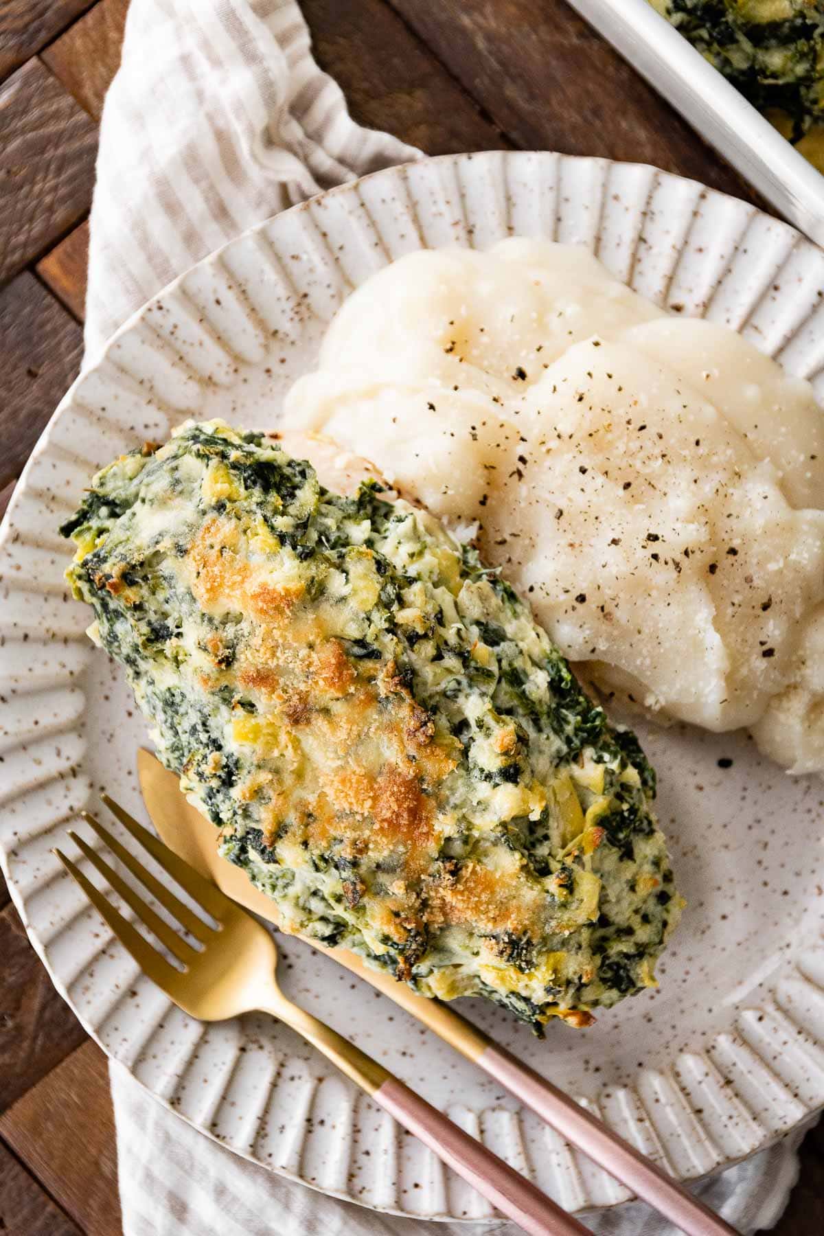 Baked Spinach Artichoke Chicken on plate with mashed potatoes