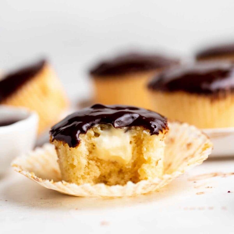 Boston Cream Cupcakes vanilla cupcake with bite exposing cream filling and chocolate ganache frosting