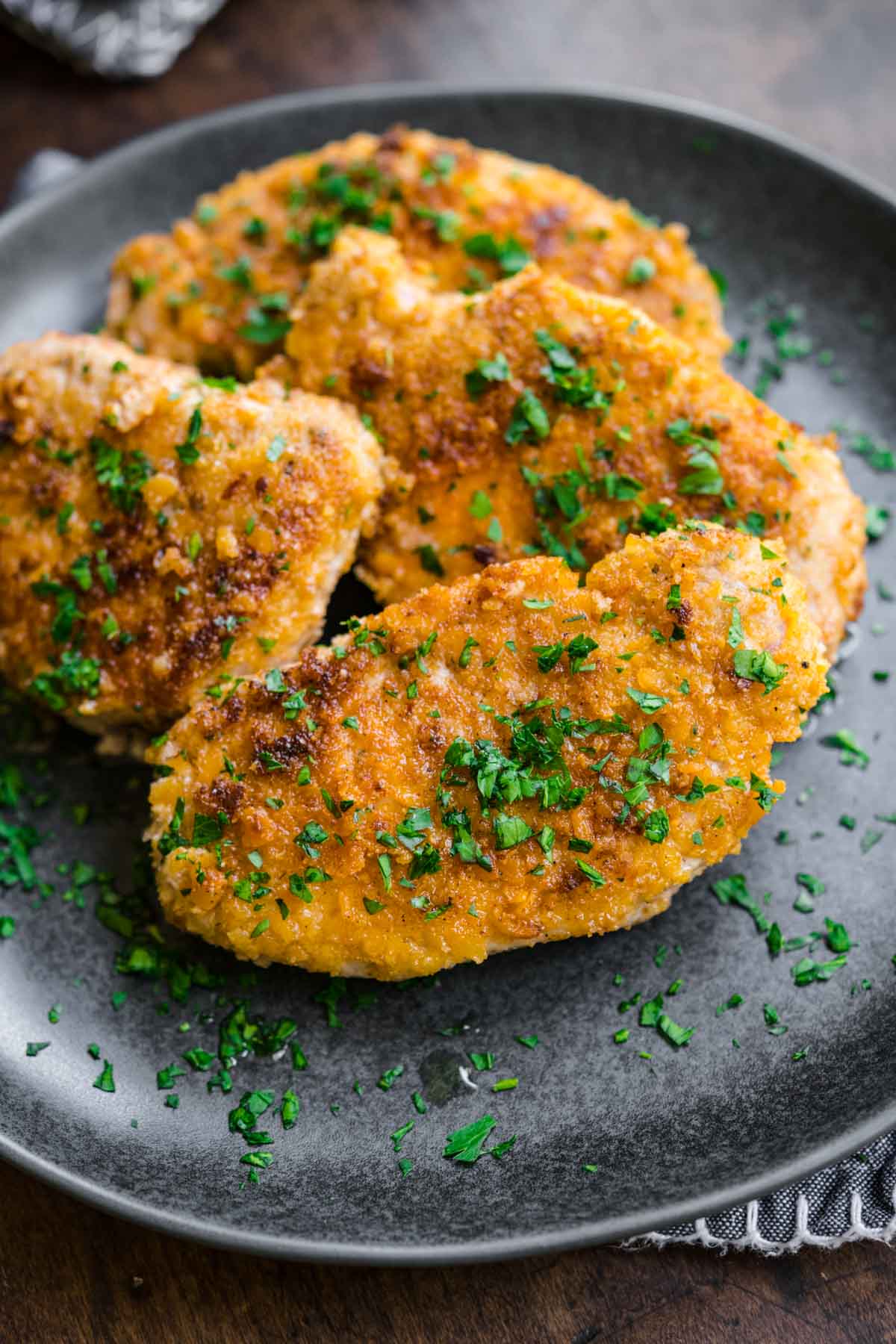 Breaded Pork Chops on serving plate with chopped fresh parsley garnish