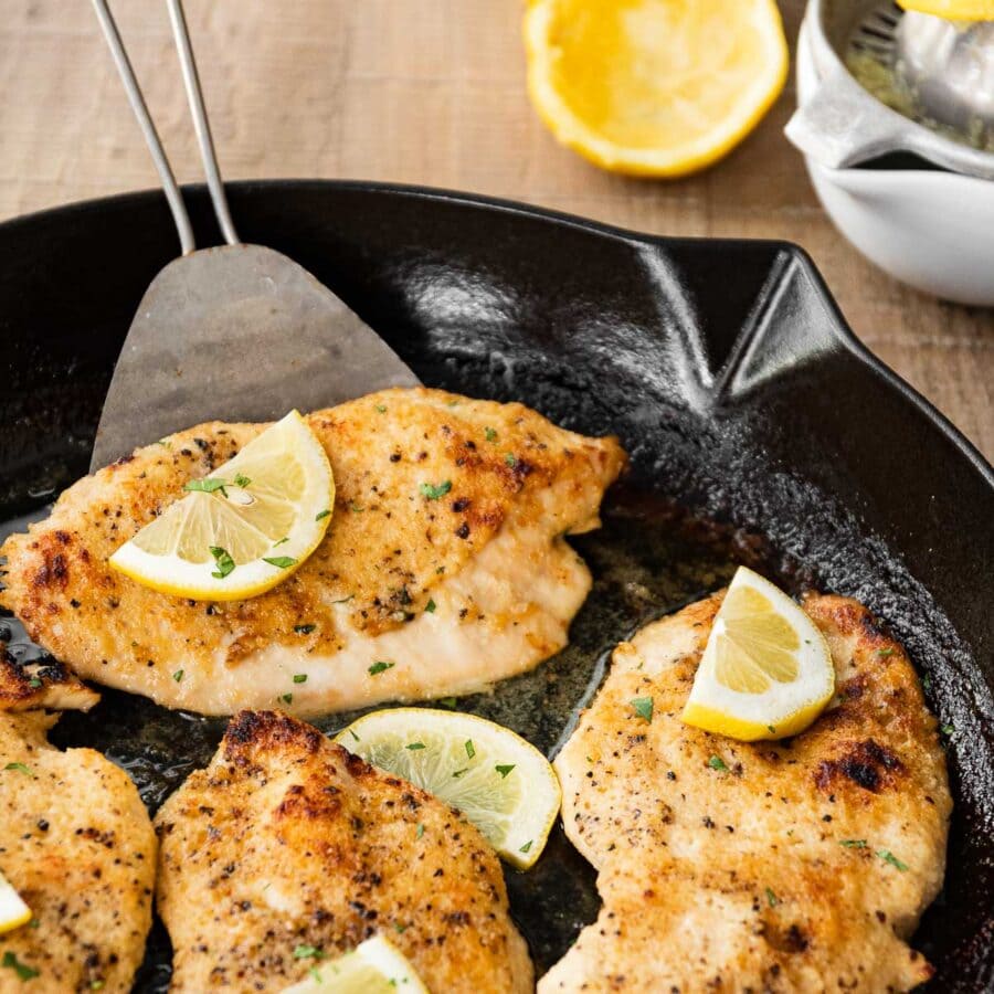 Buttery Lemon Garlic Baked Chicken in pan with lemon wedges
