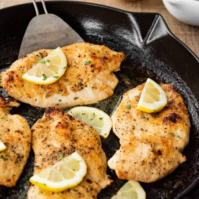 Buttery Lemon Garlic Baked Chicken in pan with lemon wedges
