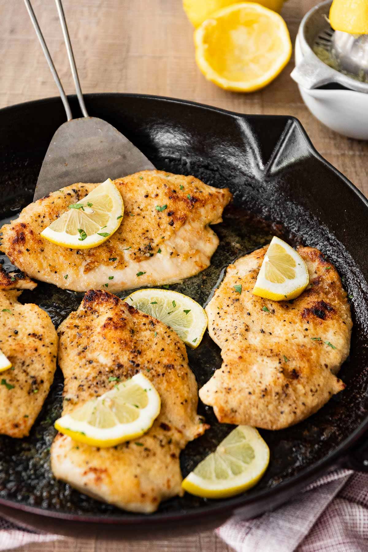 Buttery Lemon Garlic Baked Chicken in pan with lemon wedges