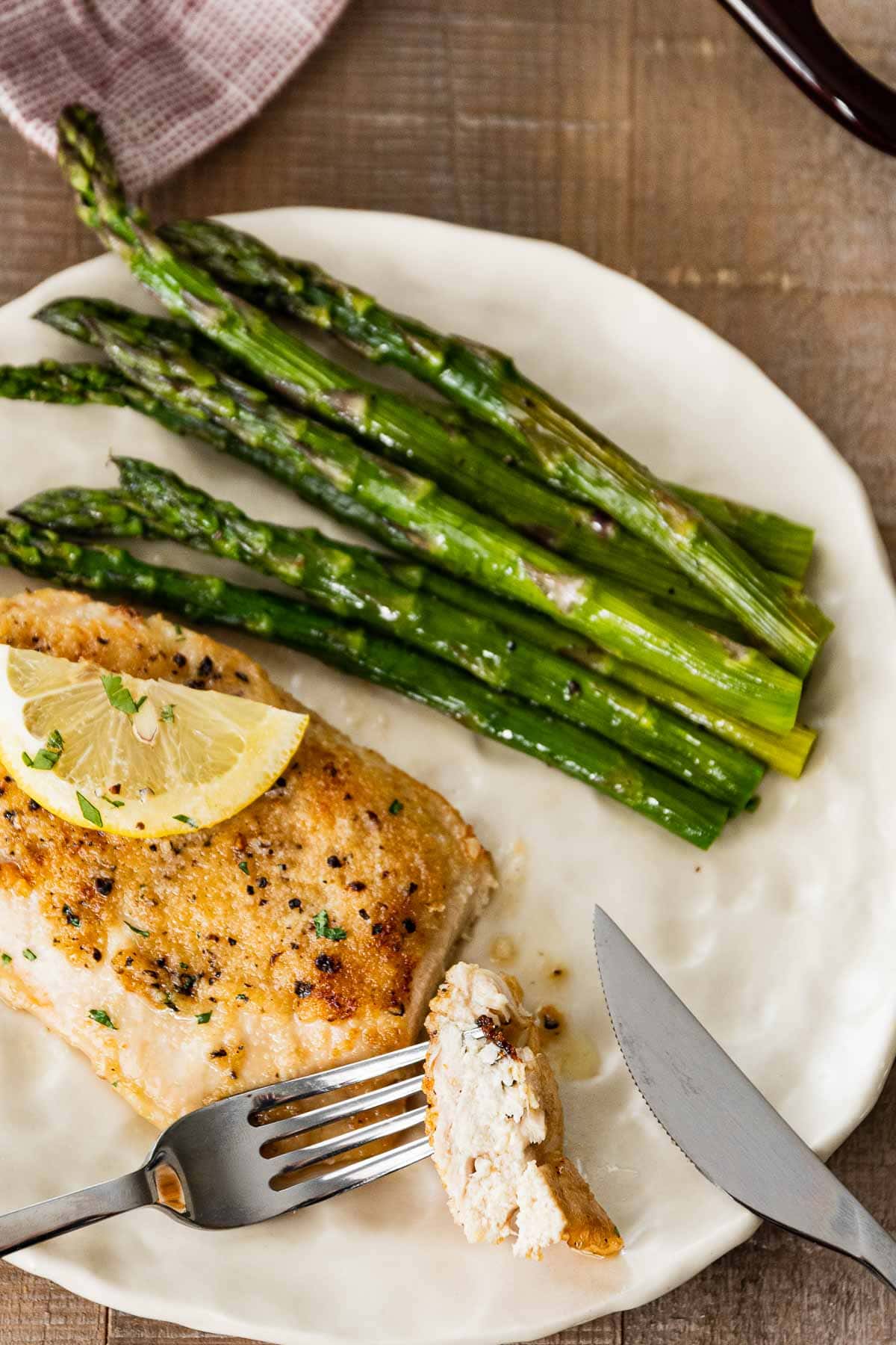 Buttery Lemon Garlic Baked Chicken on plate with asparagus