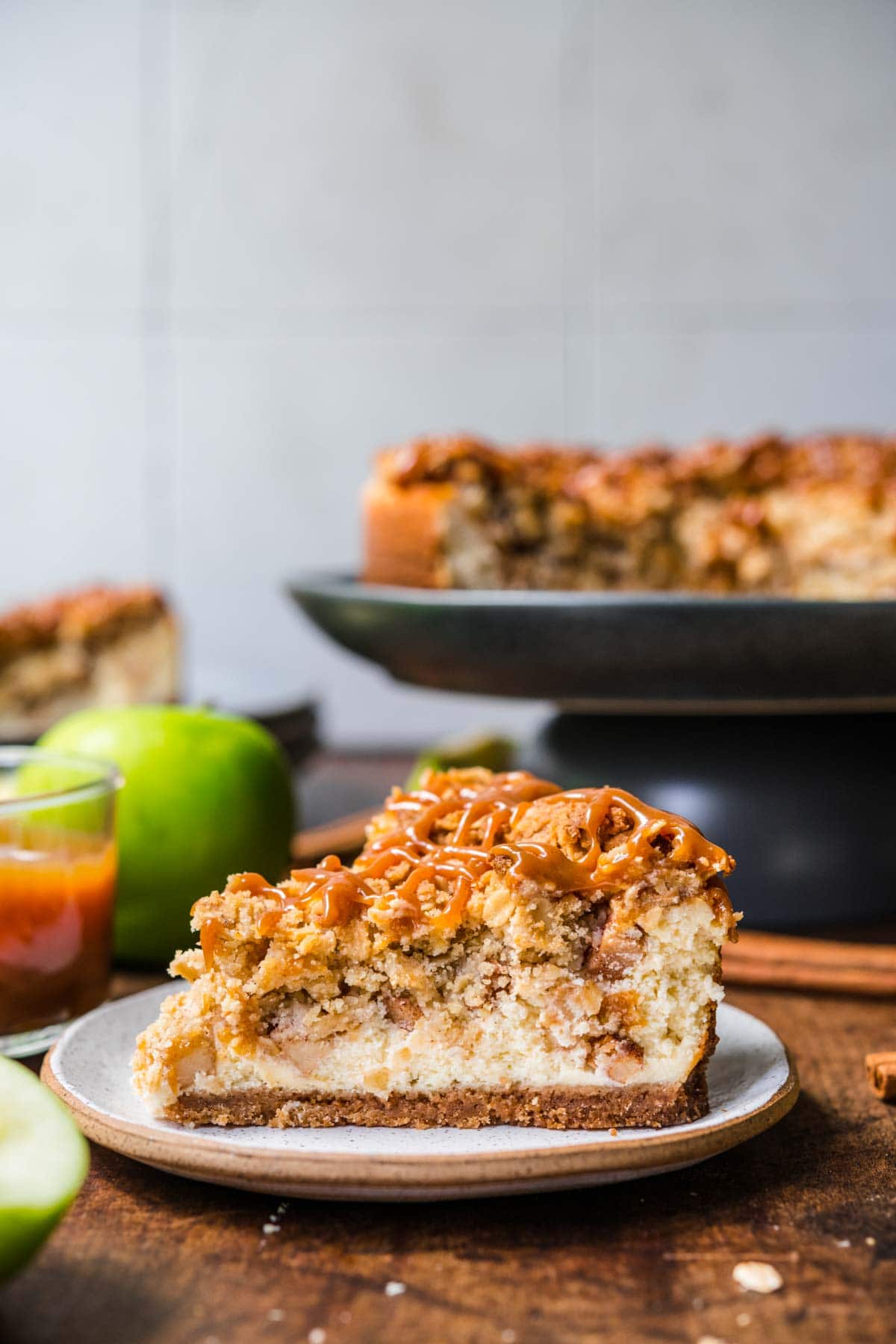 Caramel Apple Crumb Cheesecake slice on plate with caramel drizzle on top