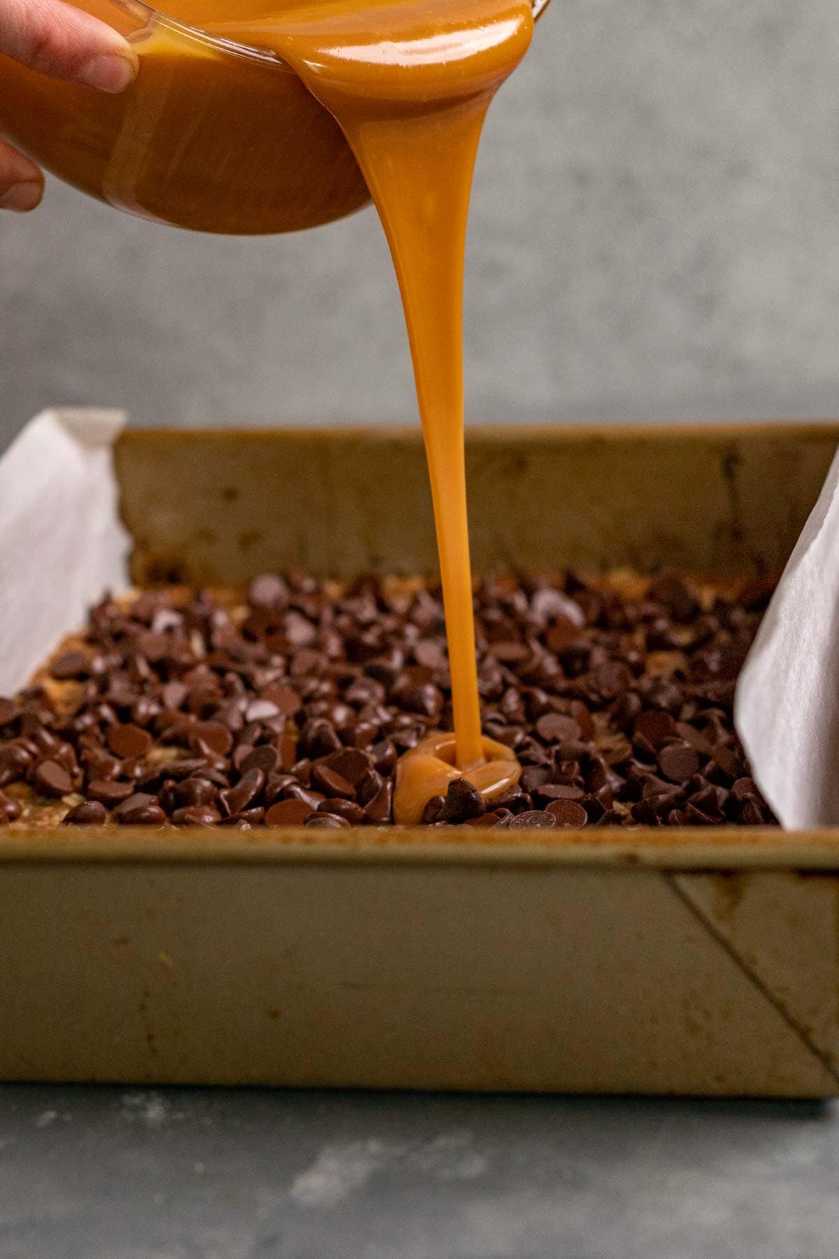 Caramel Chocolate Bars caramel sauce pouring onto chocolate chip layer