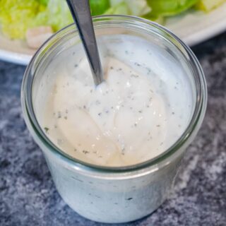 Homemade Ranch Dressing in cup with salad in background