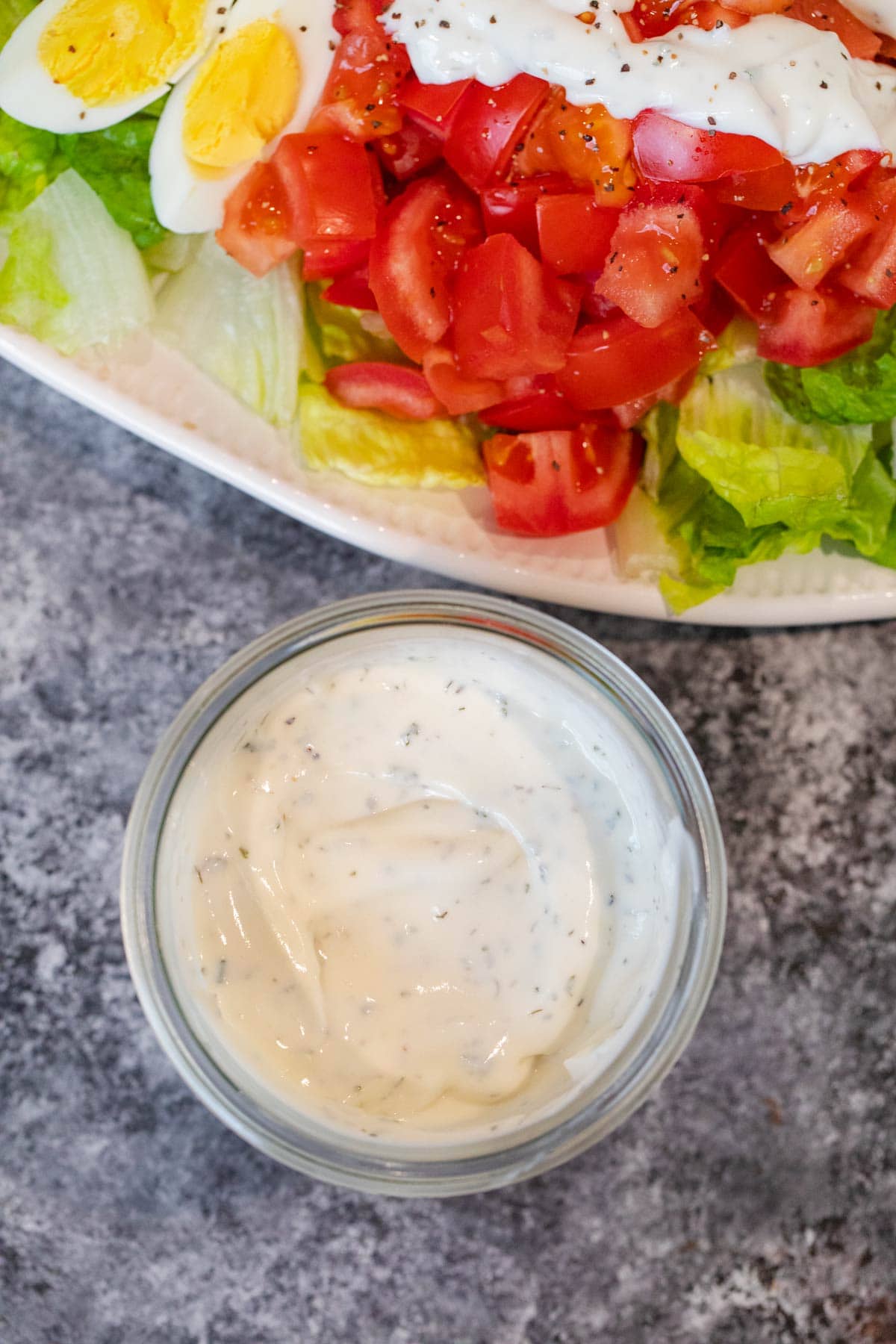 Homemade Ranch Dressing in cup with salad in background