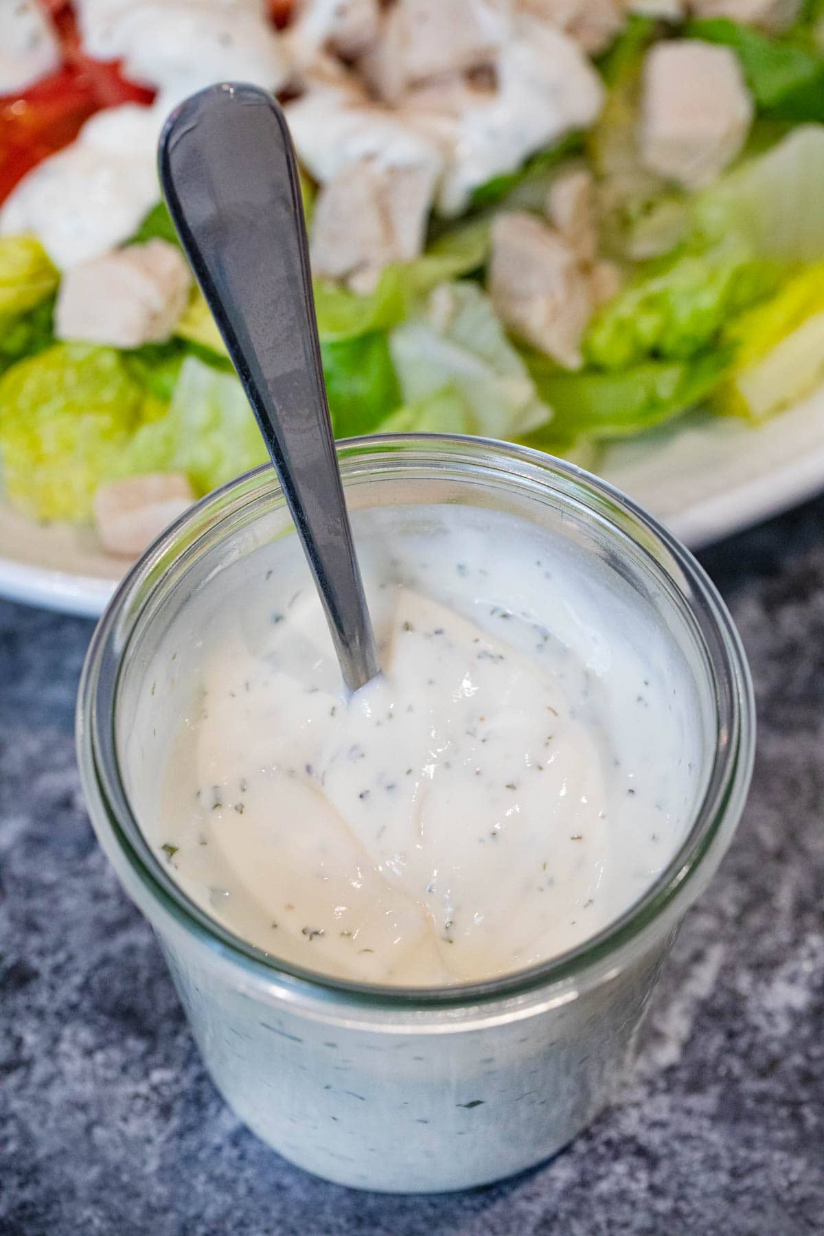 Homemade Ranch Dressing in cup with salad in background