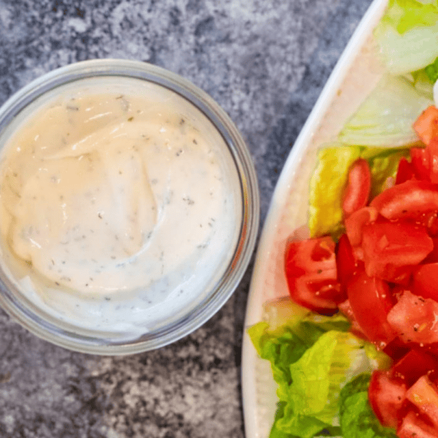 Jar of ranch next to salad