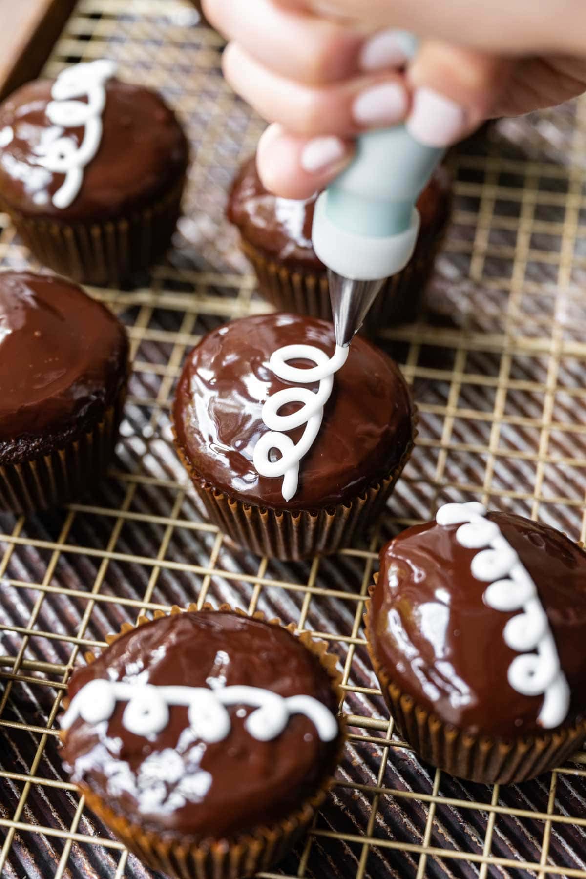 Hostess Cupcakes (Copycat) piping white frosting swirl onto ganache