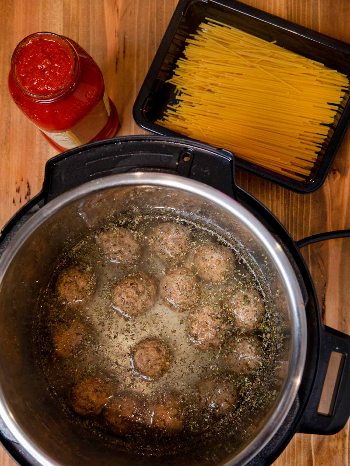 Instant Pot Spaghetti and Meatballs meatballs and water in pressure cooker with pasta and pasta sauce