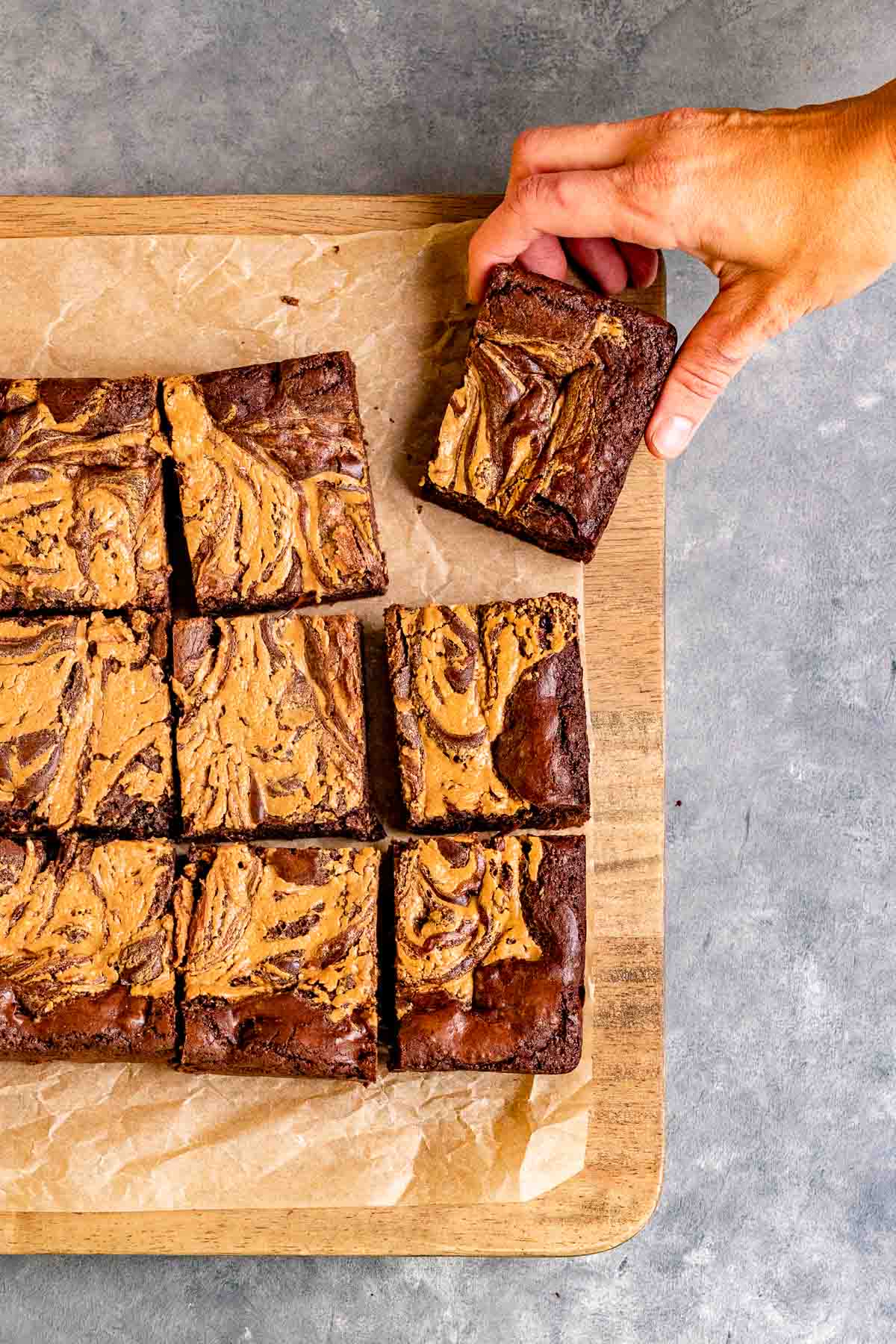 Peanut Butter Swirl Brownies sliced on parchment with hand