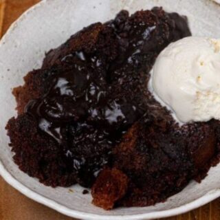 Cake in a white bowl with a scoop of ice cream.
