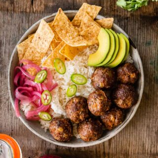 Taco Meatballs in bowl with rice, chips, avocado, jalapeños, and pickled onions
