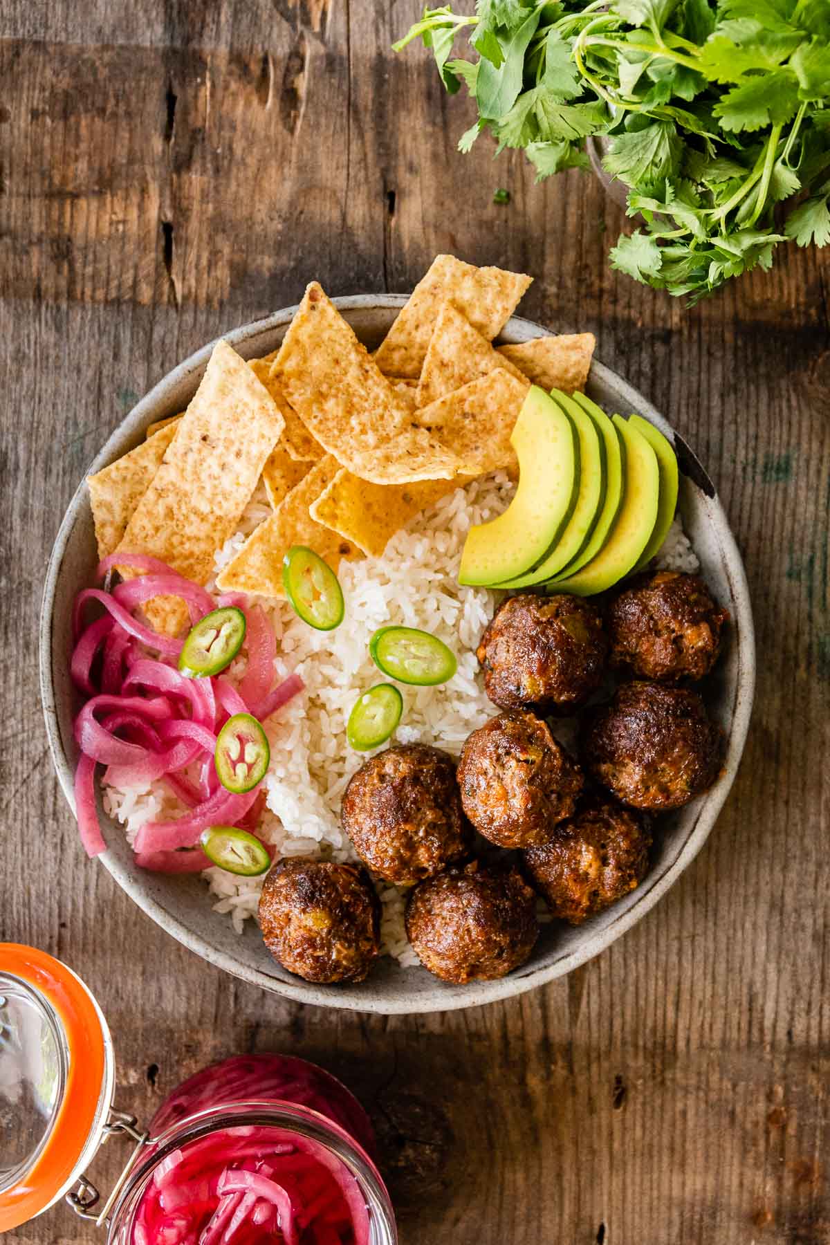 Taco Meatballs in bowl with rice, chips, avocado, jalapeÃ±os, and pickled onions