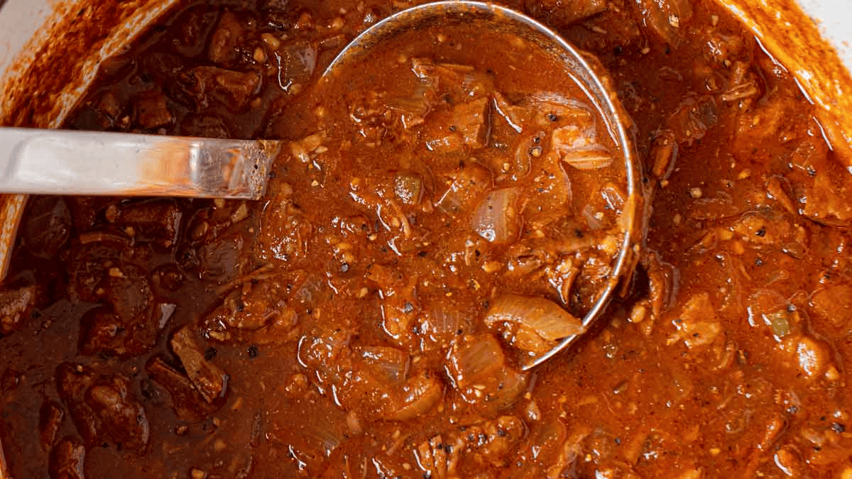 Metal ladle going into pot of chili