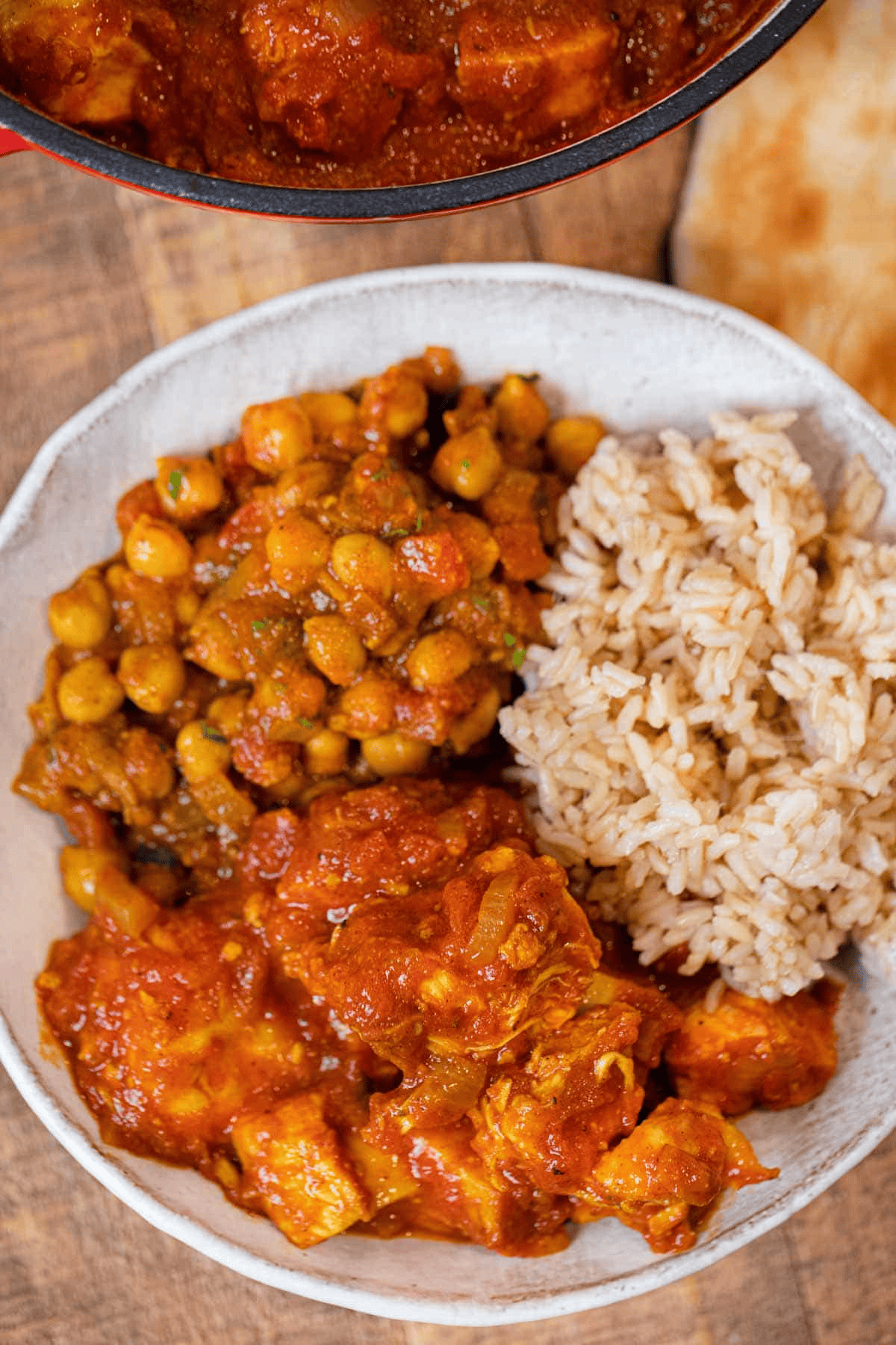 Chicken in tomato sauce plated with rice and chickpeas