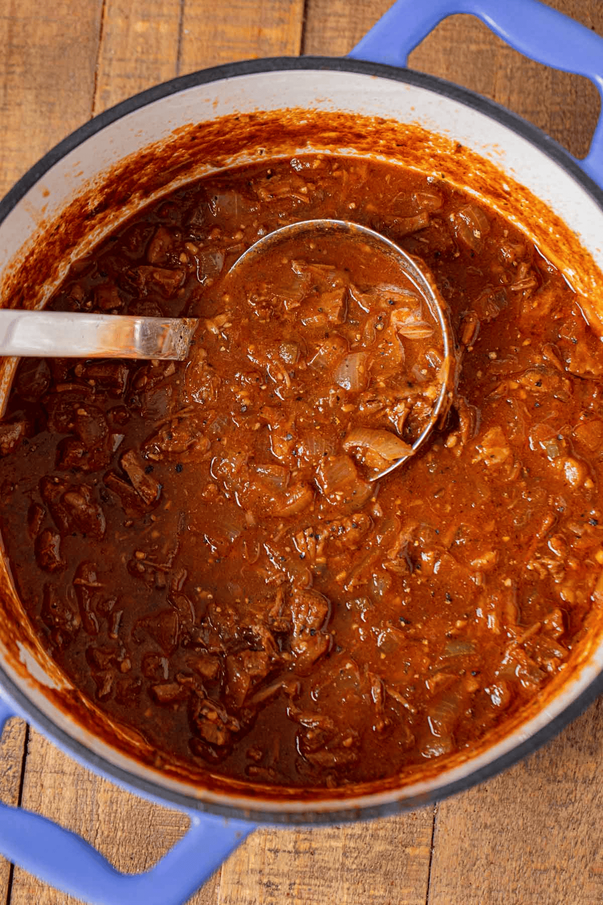 Dutch oven full of Texas chili with serving spoon