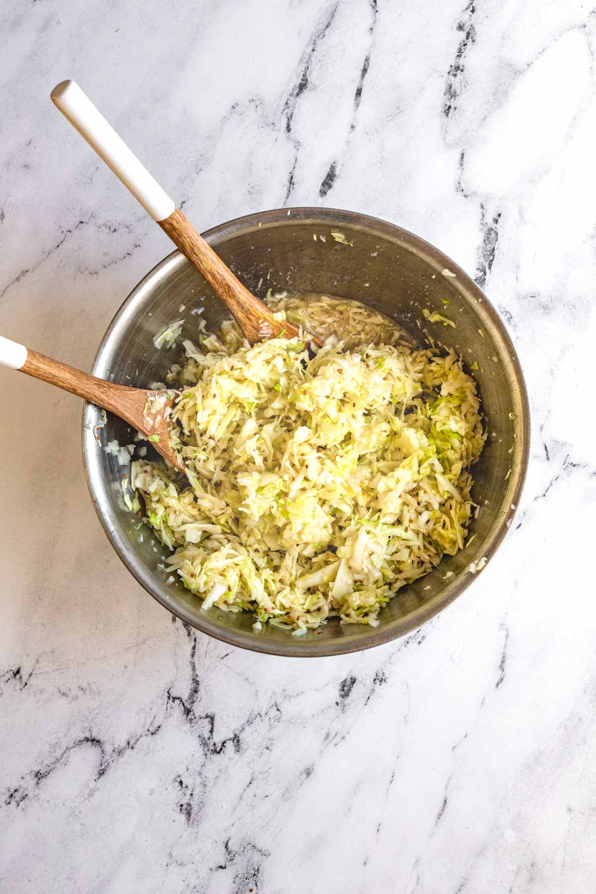 Amish Vinegar Slaw in mixing bowl with serving spoons