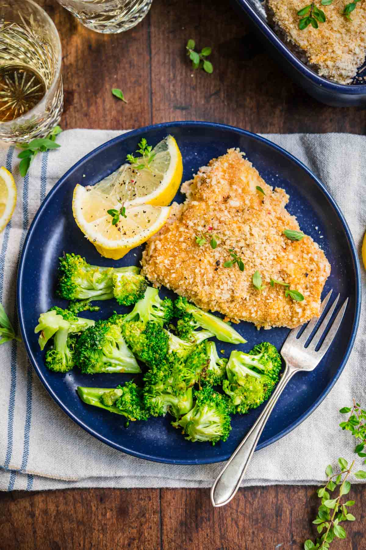 Baked Cod with lemon wedge garnish on plate with broccoli and fork