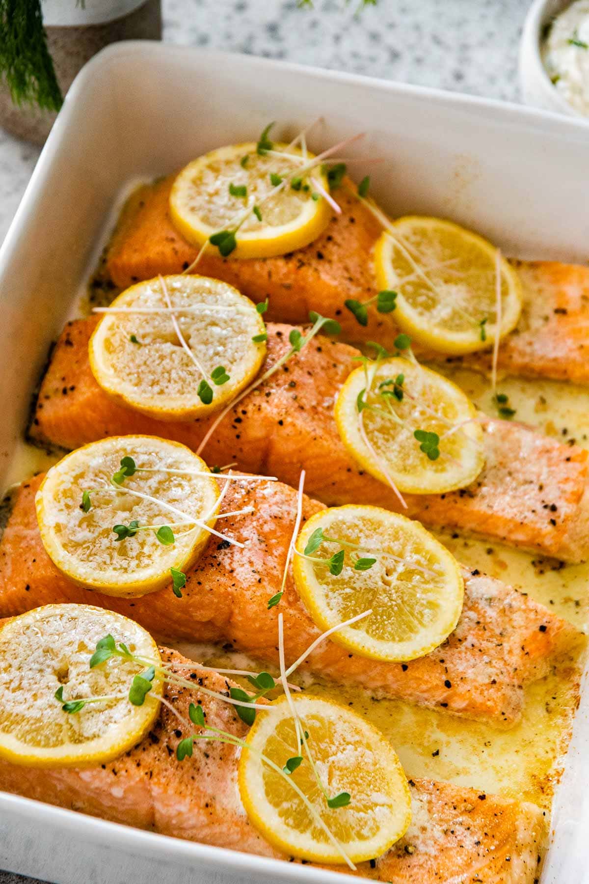 Baked Salmon with Dill Sauce salmon filets in baking dish with lemon slices after baking