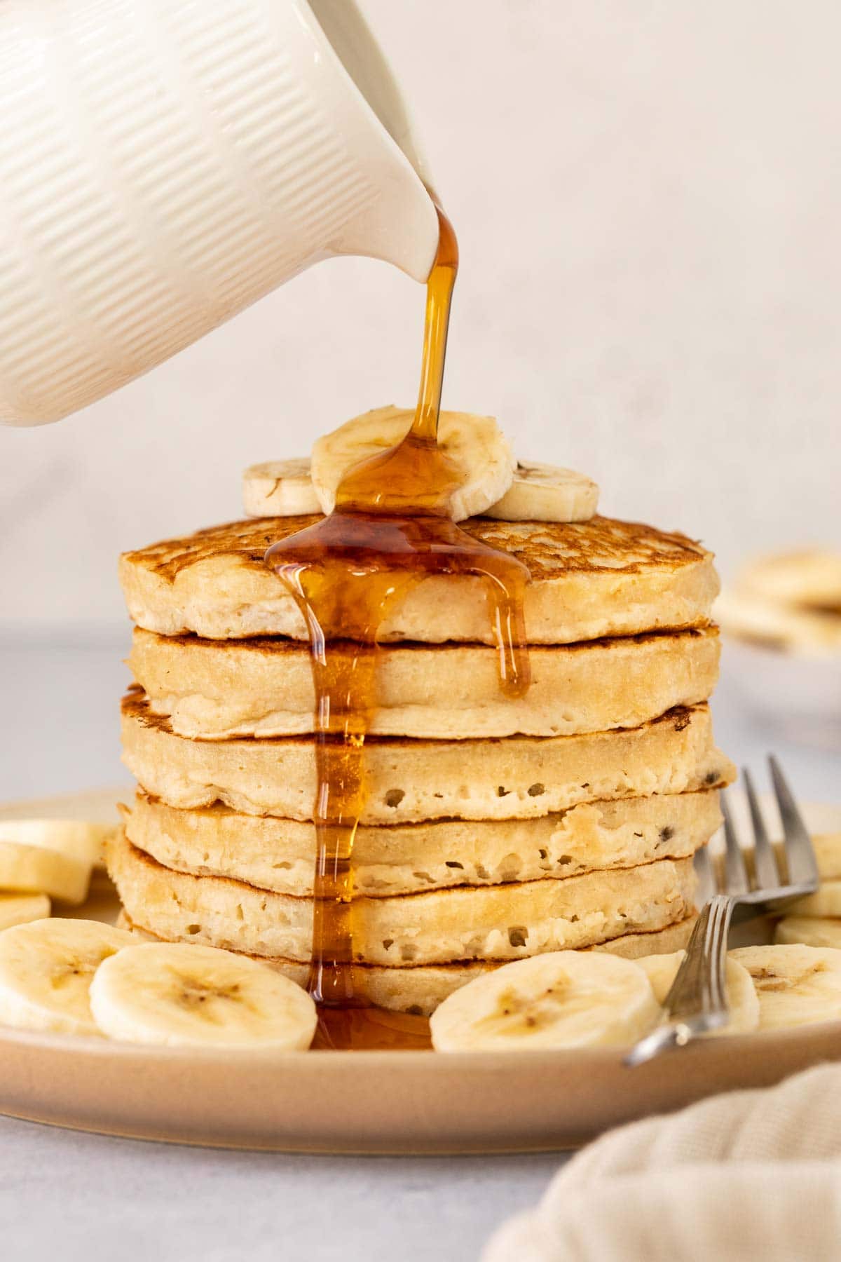 Banana Pancakes pouring syrup on stack