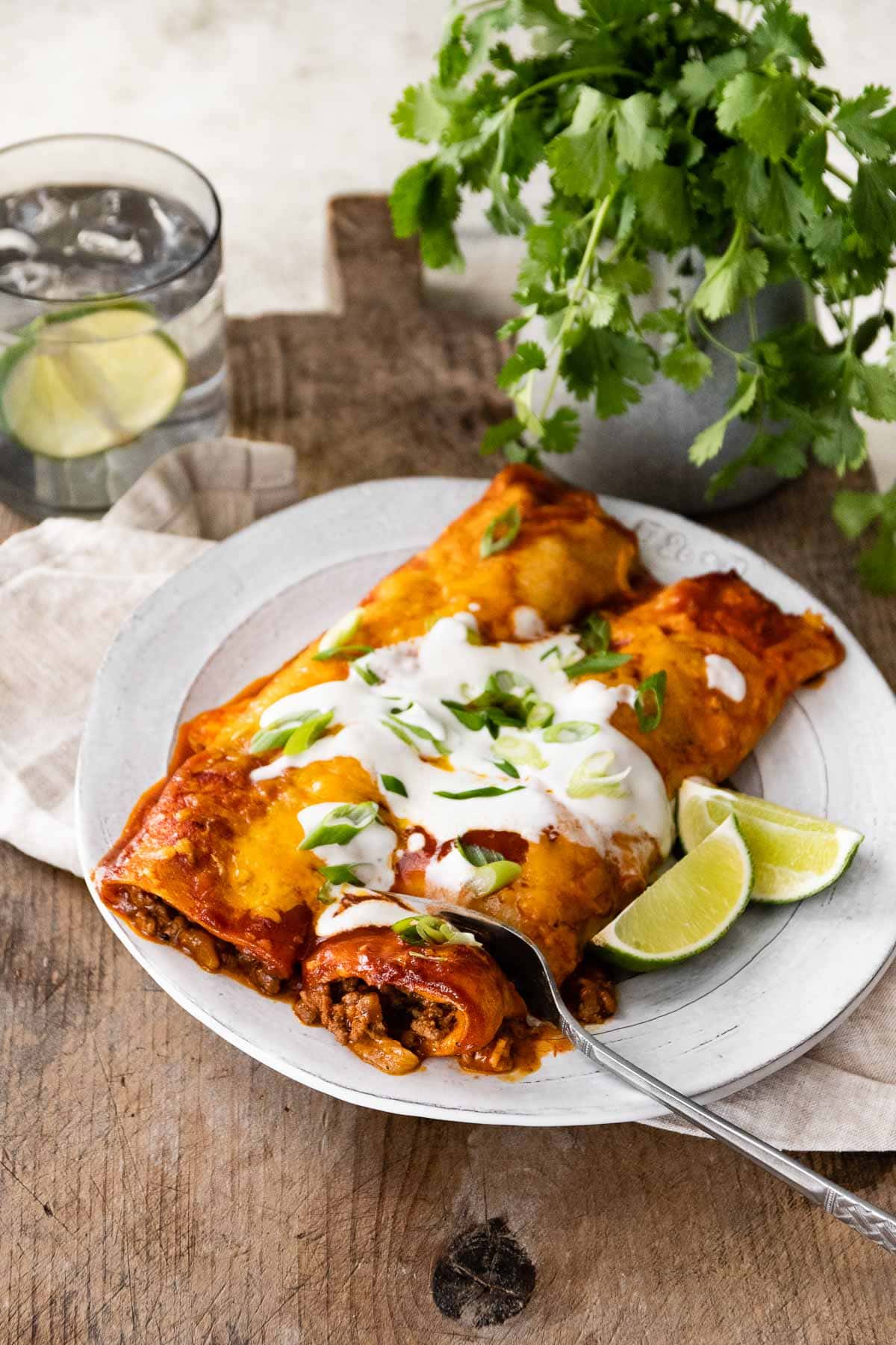 Beef Enchiladas on plate with lime wedges and fork