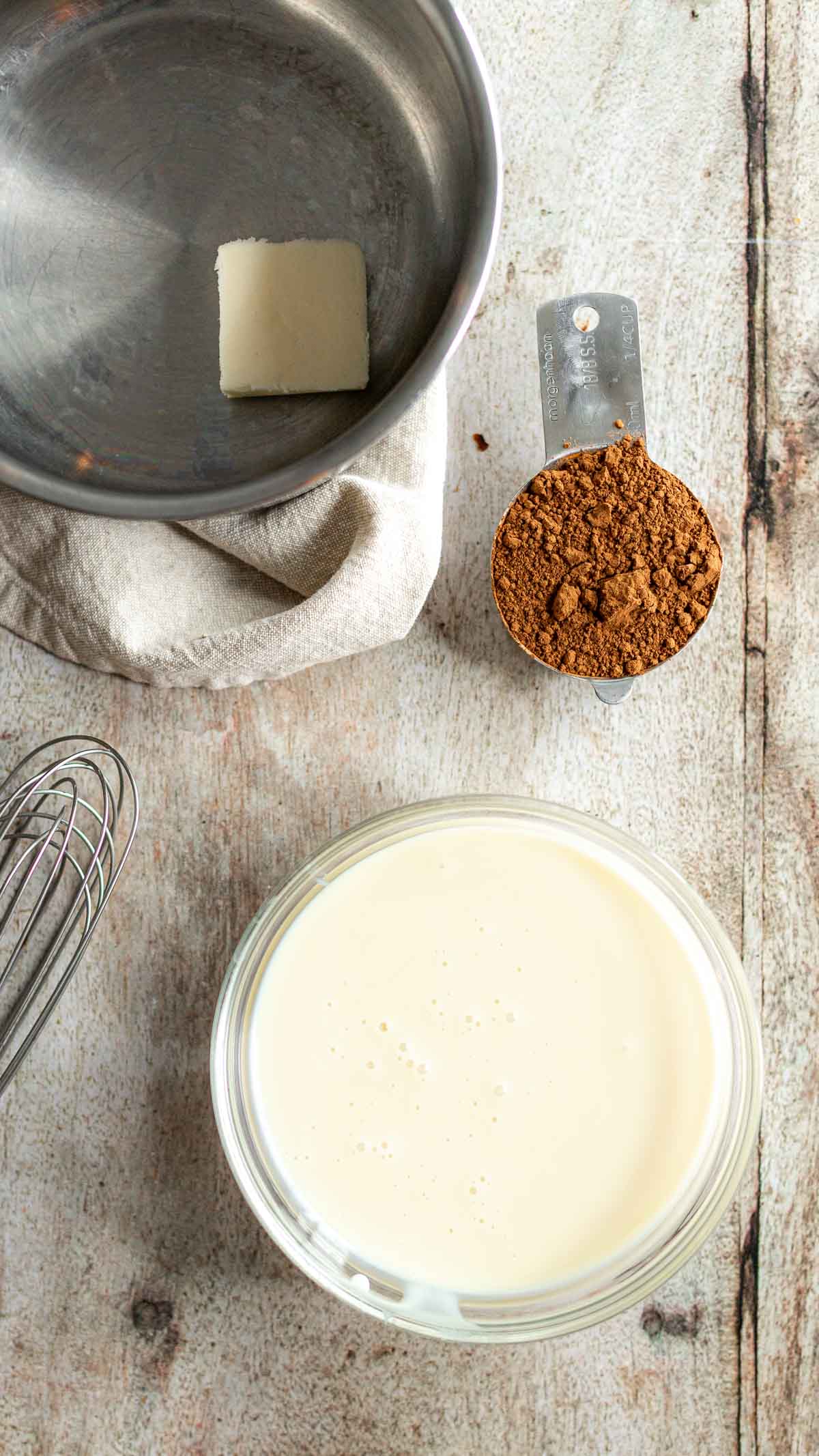 Sauce pot with butter, bowl of sweetened condensed milk, and cocoa powder in measuring cup for Brazilian Brigadeiros Candies