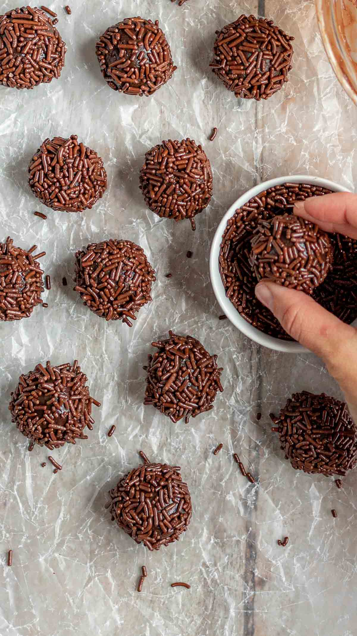 Brazilian Brigadeiros Candies balls with hand dipping in chocolate sprinkles