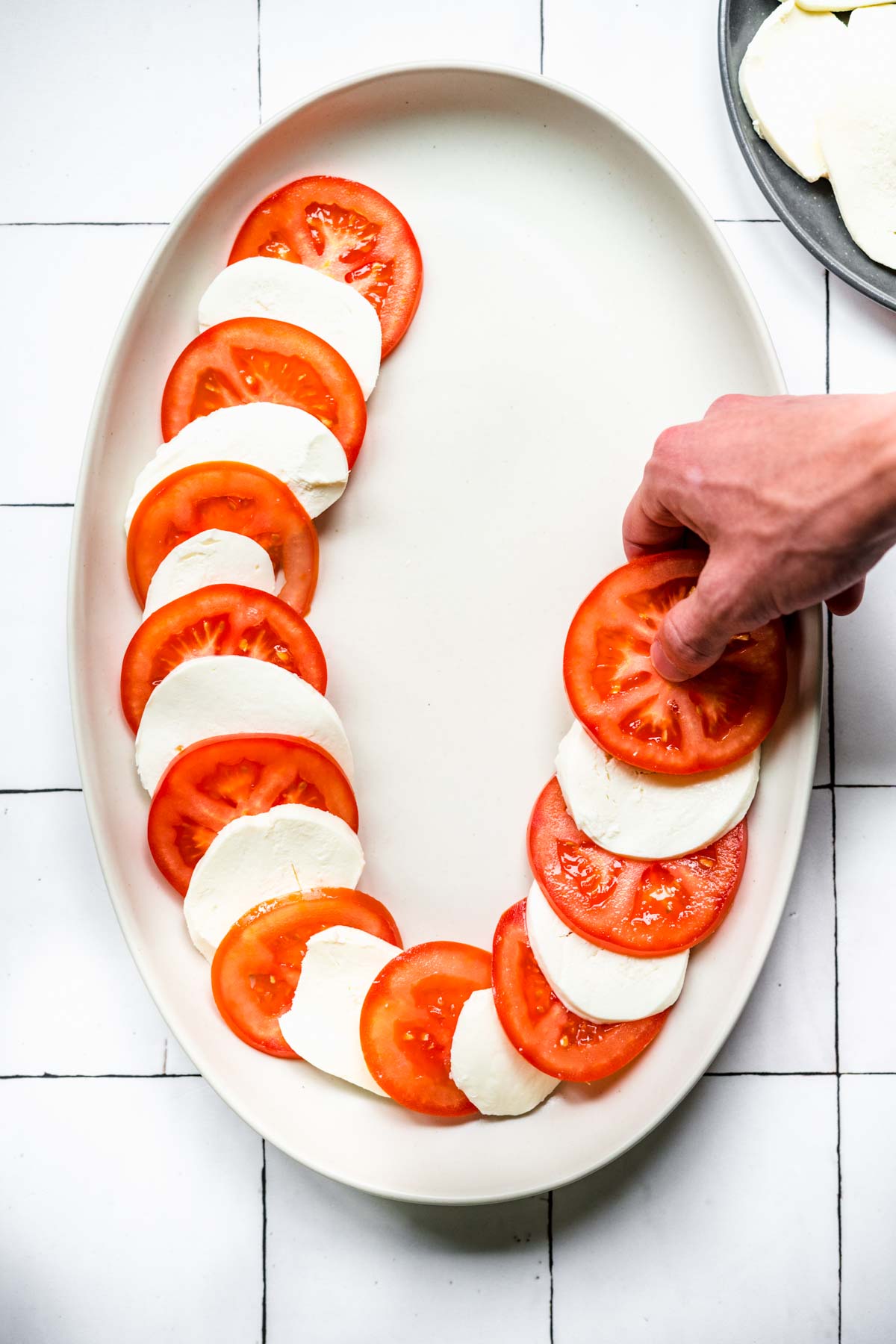 Arranging tomato and mozzarella slices on serving platter for Tomato Mozzarella Salad